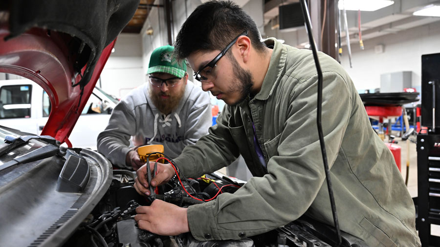 Two students working under the hood of a car