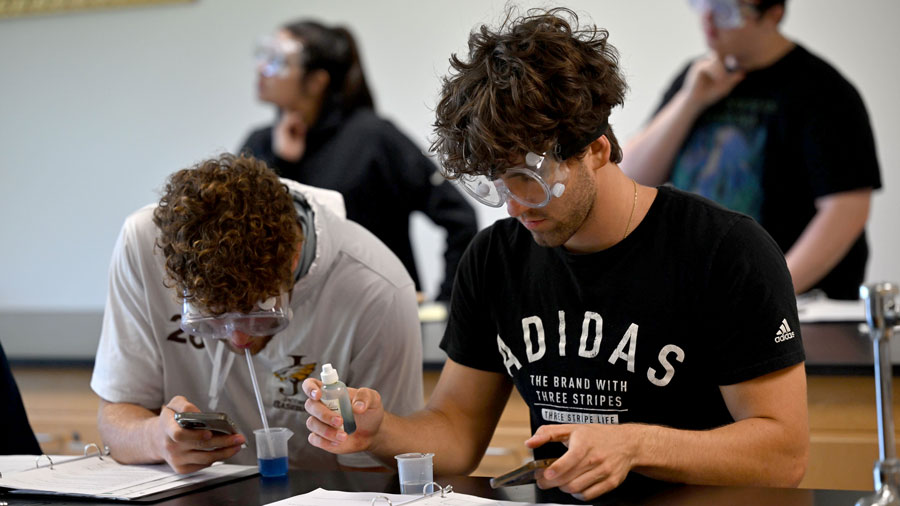 Two students wearing eye protection in a science lab