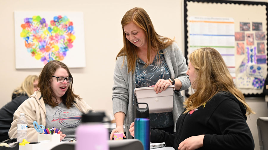 Instructor working with two students at a table