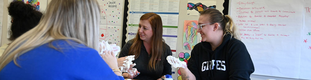 Four students sitting at a table working on a craft project