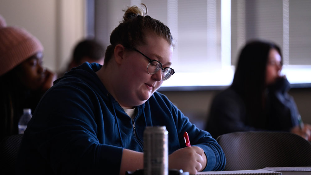 Student writing at a desk