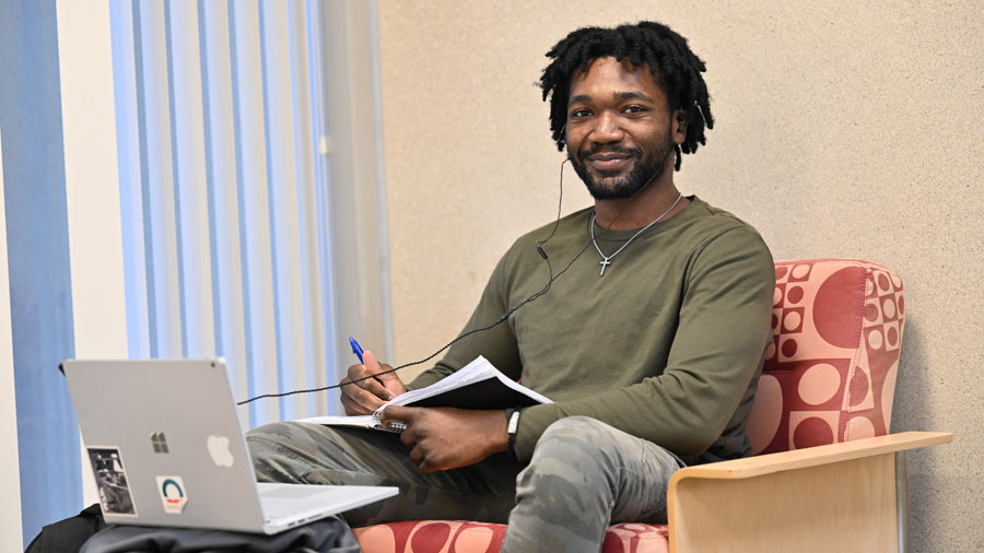 Student taking notes while sitting at their laptop