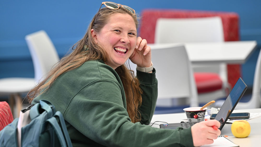 Smiling student sitting in front of their laptop