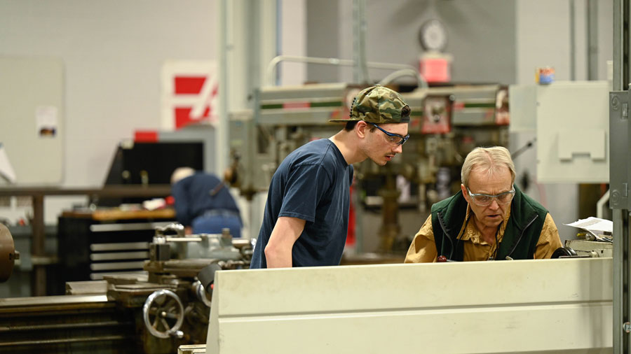 Instructor working with a student on a metal lathe
