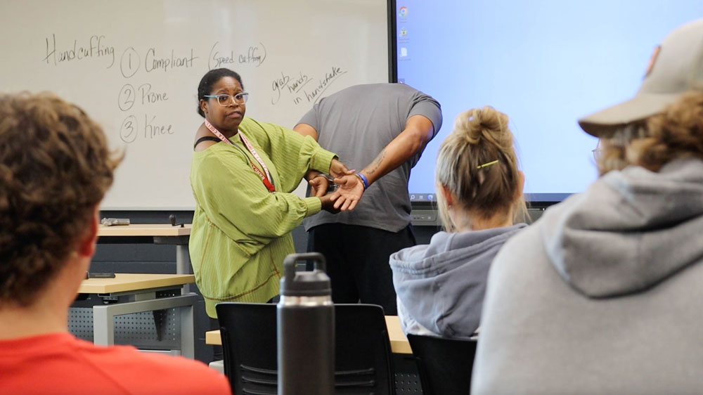 Instructor doing a handcuffing demonstration at the front of the classroom