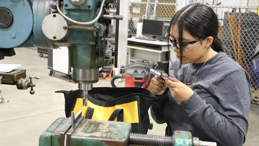 Student using a micrometer while working on a milling machine