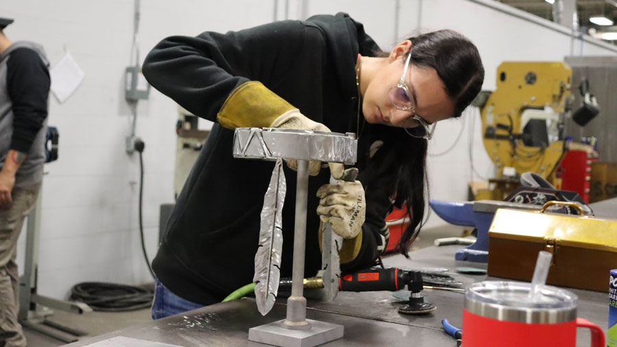 Student working with a welded piece of metal