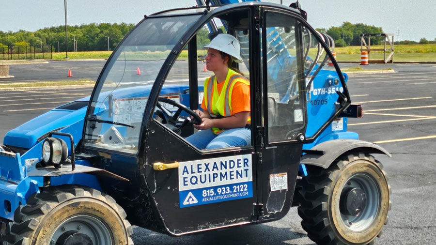 Student wearinga a helmet and high-visibility vest driving a telescopic handler
