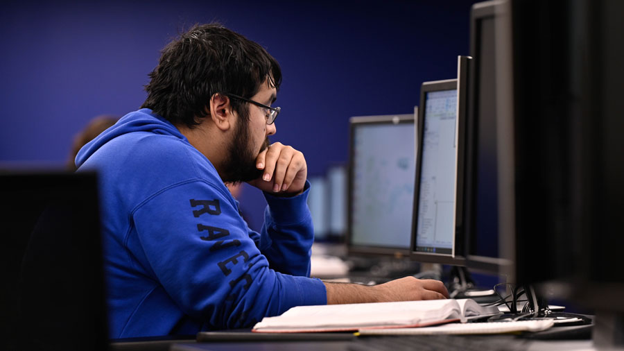 Student working at a dual-monitor PC workstation