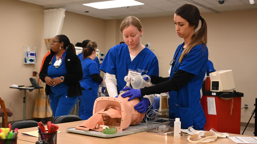 Two resipiratoy therapist students doing a training exercise with more students in the background
