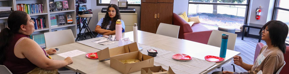 Three students sitting around a table having a discussion