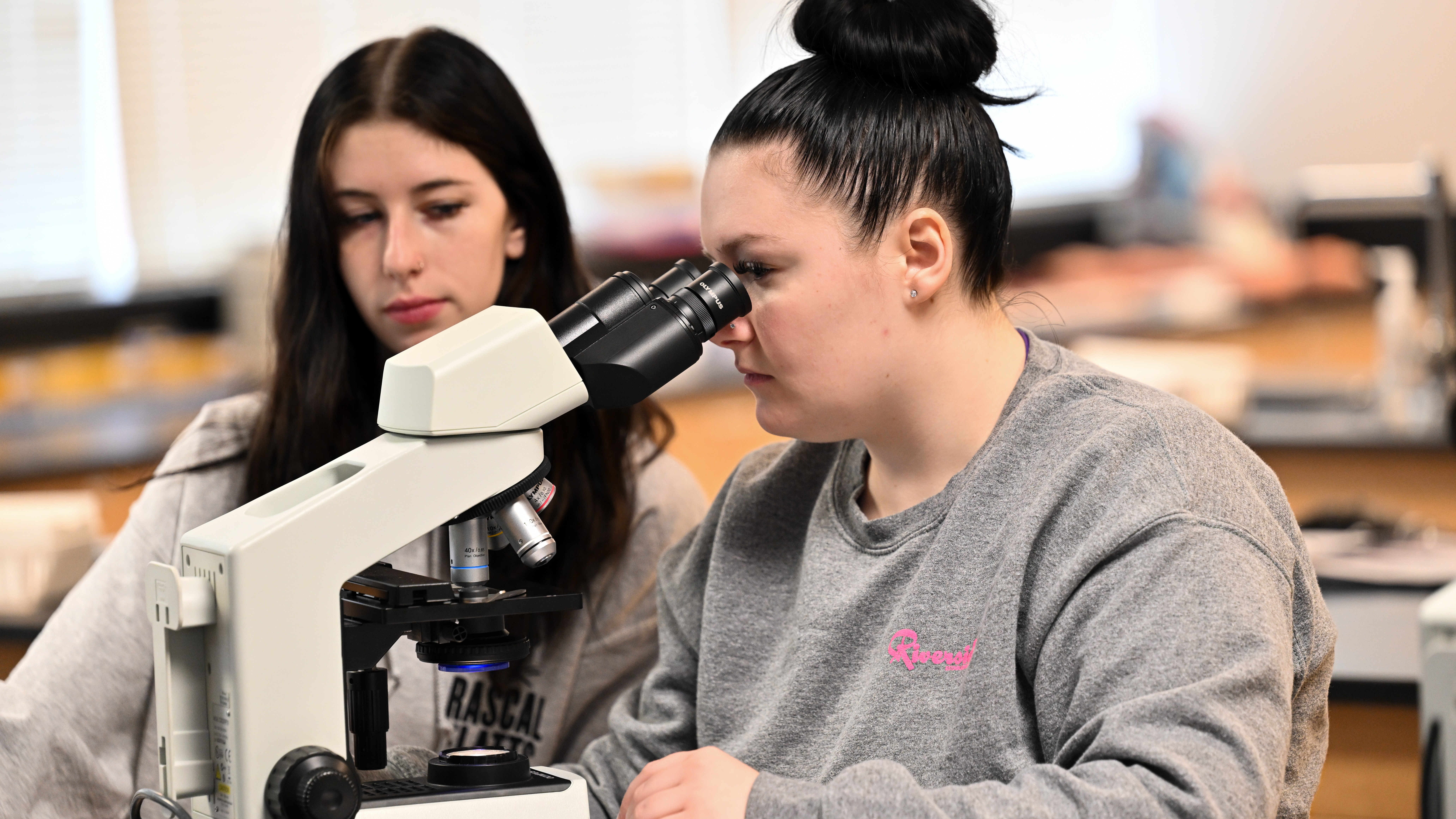 Two students in a classroom looking through a telescope. 