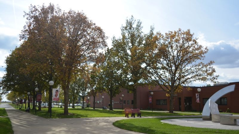 Front entrance of KCC with a sculpture and trees from left to right leading down the lawn.
