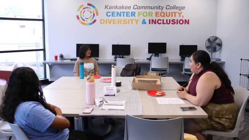 2 students sitting down with Melany Villagomez having a discussion in the EDI Center